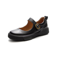 A single black cow leather Mary-Jane shoe with a thick sole and a gold buckle detail. The shoe has a round toe, set against a white background. 