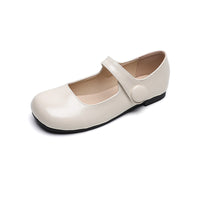 A single beige Mary-Jane flat shoe with a smooth leather finish, featuring a strap and a round button detail.